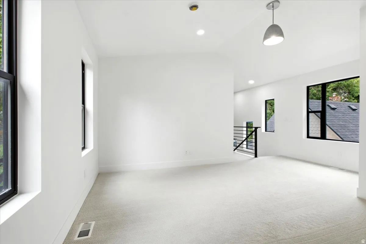 Expansive room featuring light-toned carpeting and multiple black-framed windows