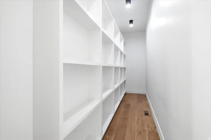 Built-in white shelving system featuring multiple cubbies, wood-finish flooring, and recessed ceiling lighting