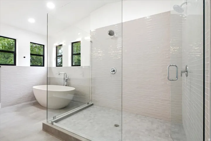Contemporary bathroom featuring a freestanding soaking tub, glass-enclosed shower with subway tile walls, dual shower heads, and recessed lighting