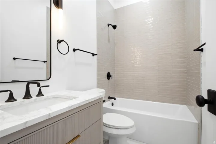 Contemporary bathroom featuring a light gray vanity with a stone countertop, an undermount sink, and matte black fixtures