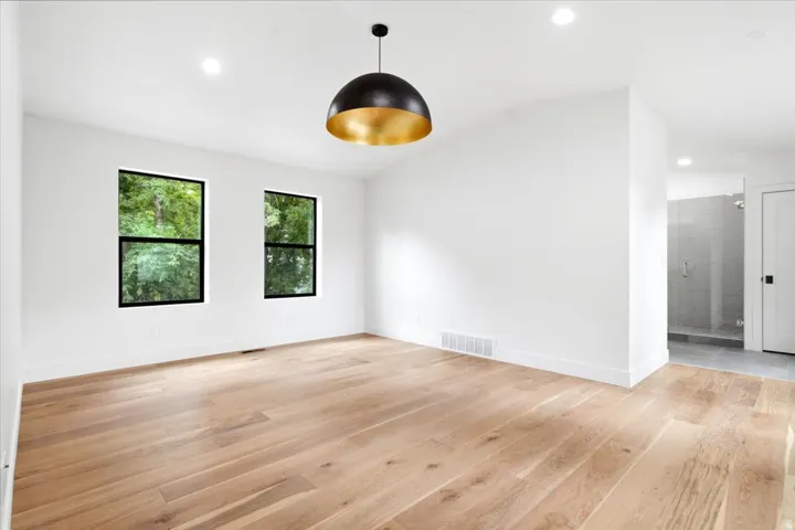Primary Bedroom featuring wood-finish flooring, recessed lighting, and a contemporary black and gold pendant light fixture