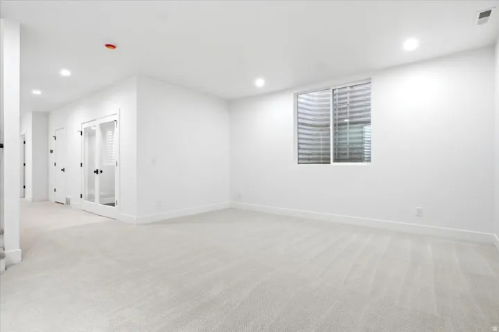 Expansive room featuring light gray carpeting and bright white walls