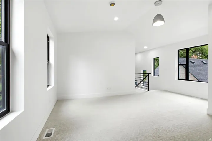 Expansive room featuring light-toned carpeting and multiple black-framed windows
