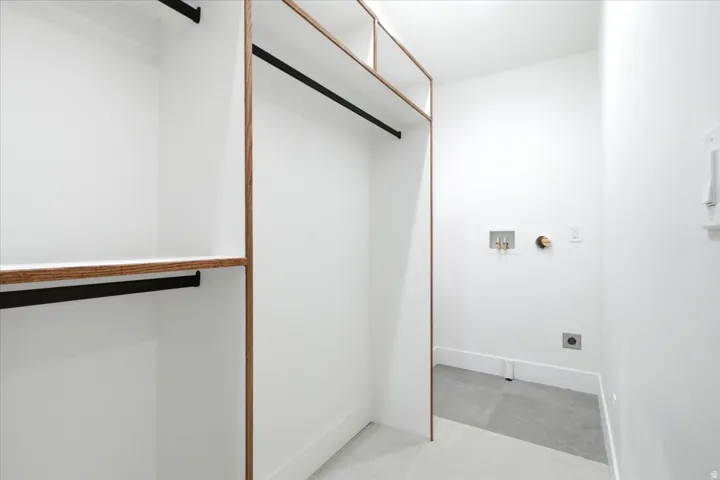 Primary Custom closet system featuring wood-finish framing and integrated shelving. Washer and dryer hookups