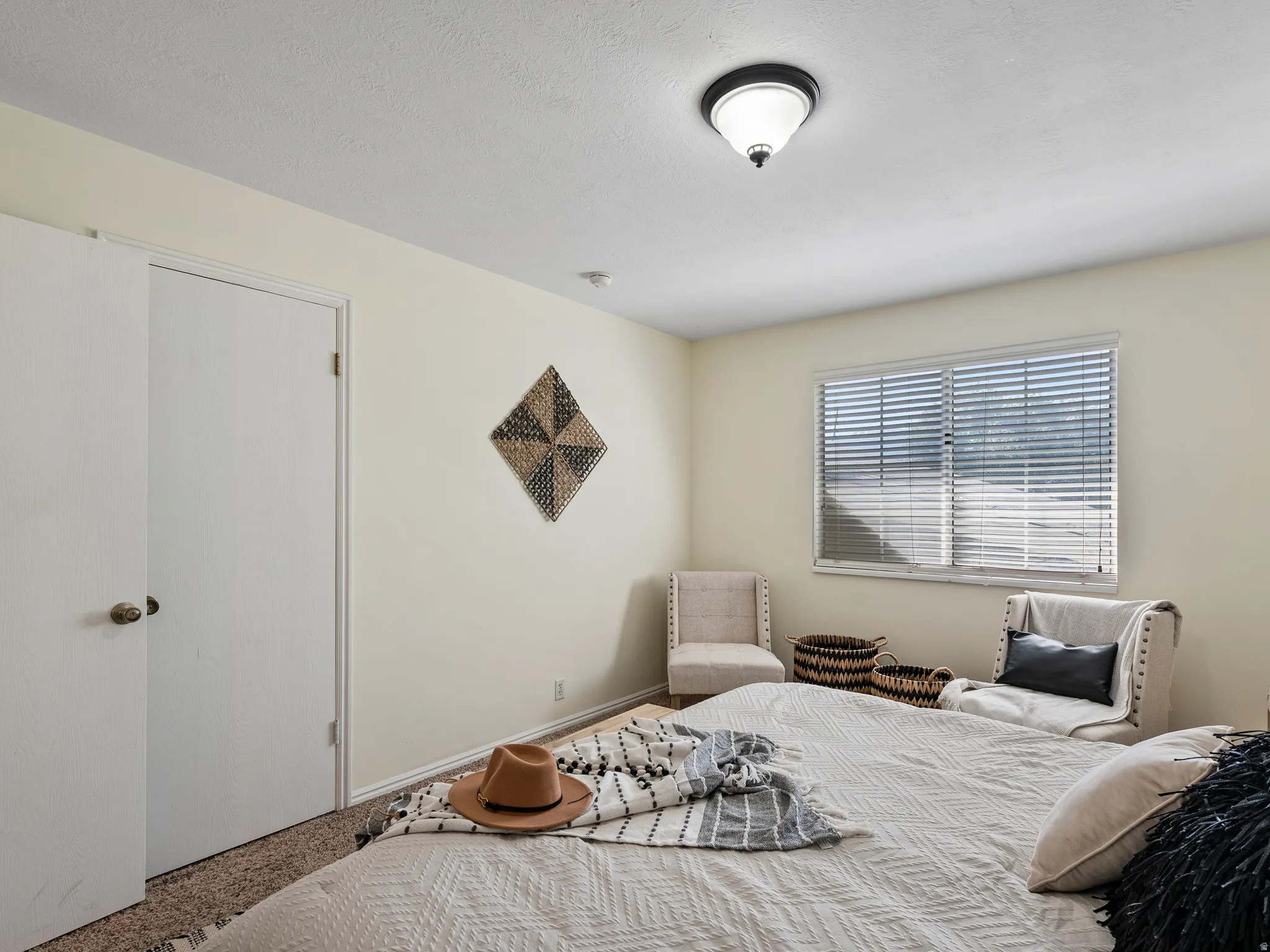 Carpeted room with a ceiling-mounted light fixture, louvered window blinds, and white doors