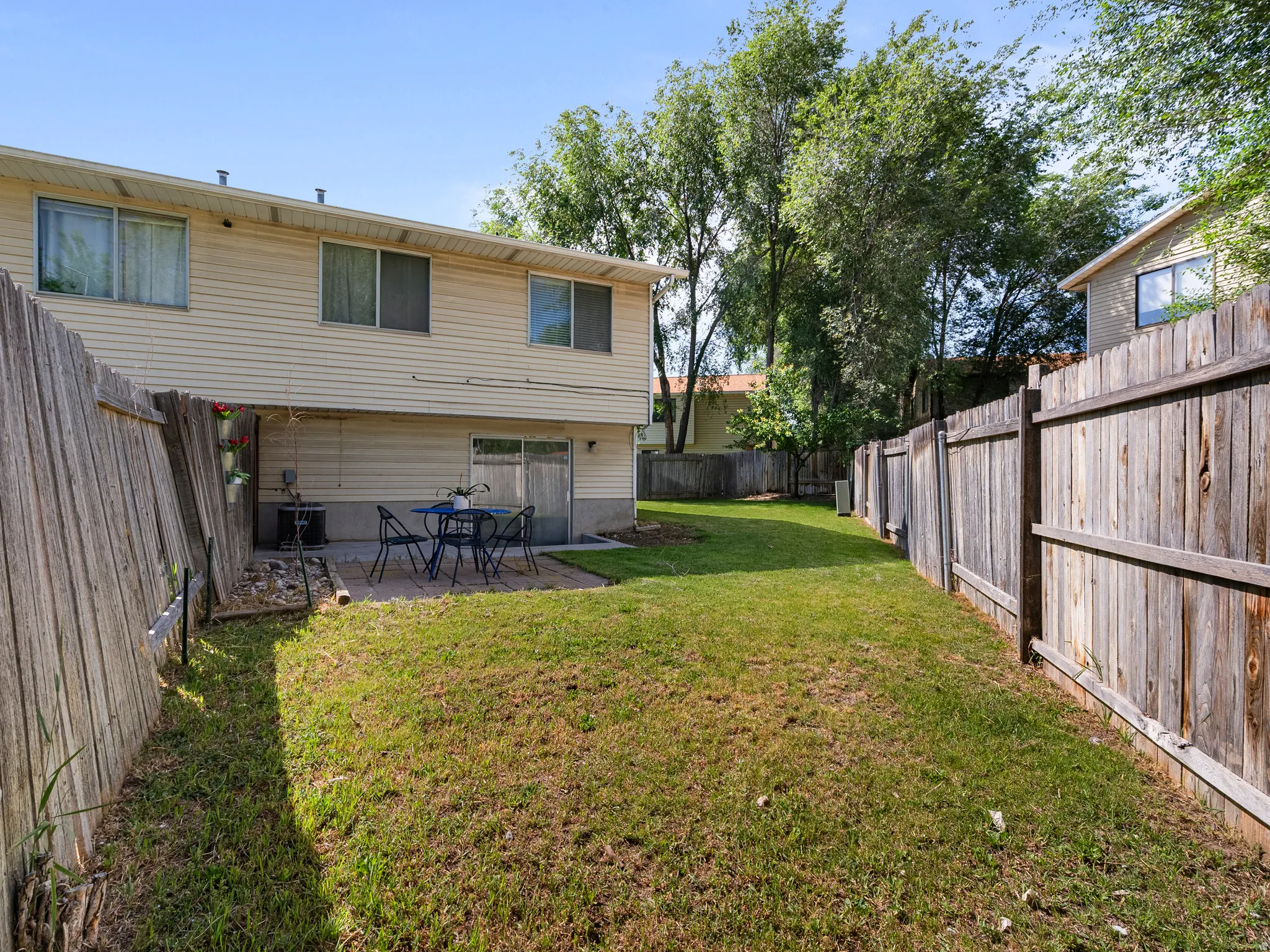 Fenced backyard featuring a manicured lawn, a concrete patio, and a sliding glass door