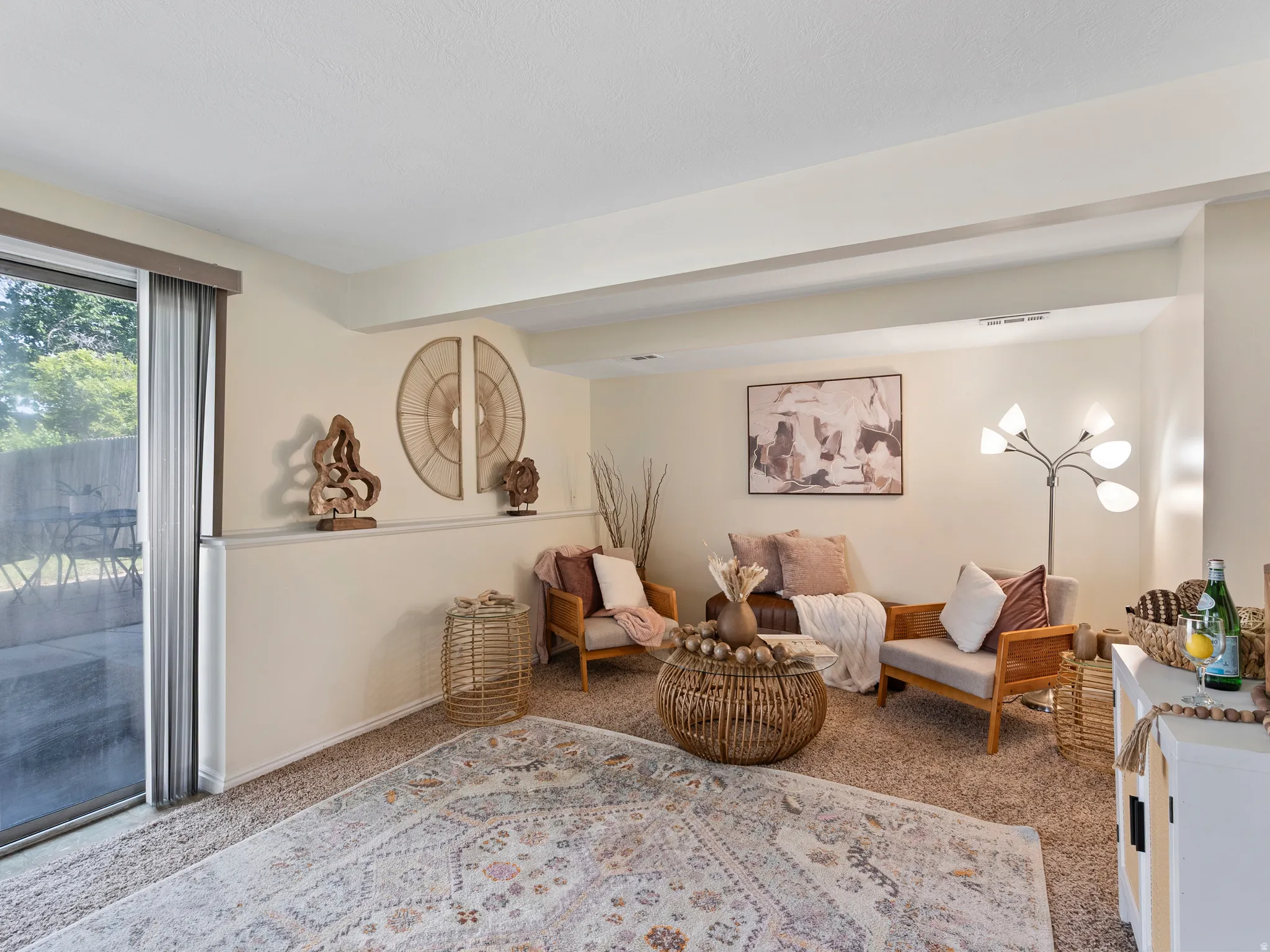 Carpeted living space featuring cream walls and a sliding glass door