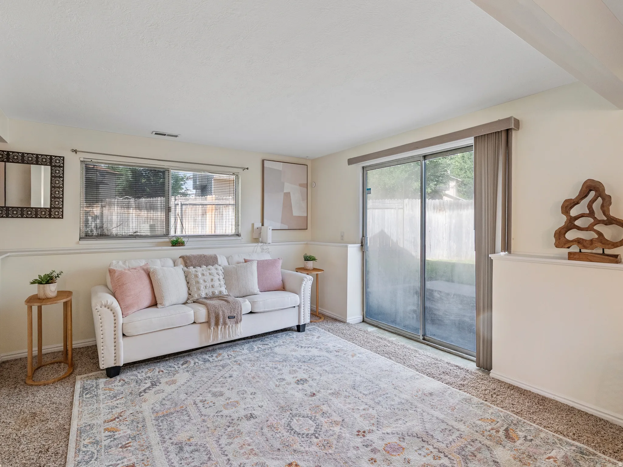 Carpeted interior space featuring a large window, sliding glass door, and white baseboards
