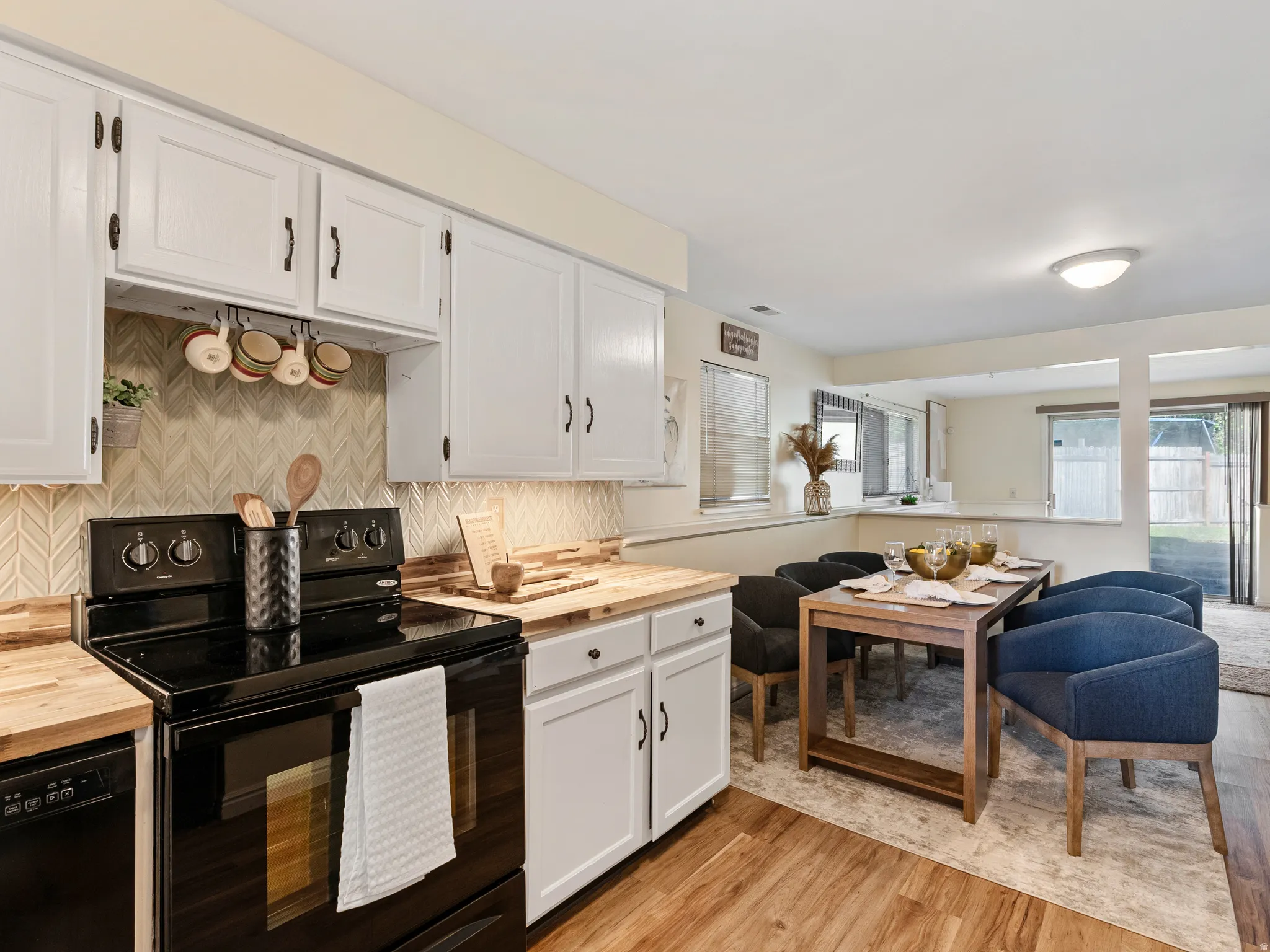 Kitchen featuring white cabinetry, light wood-finish countertops, and a herringbone-patterned tile backsplash