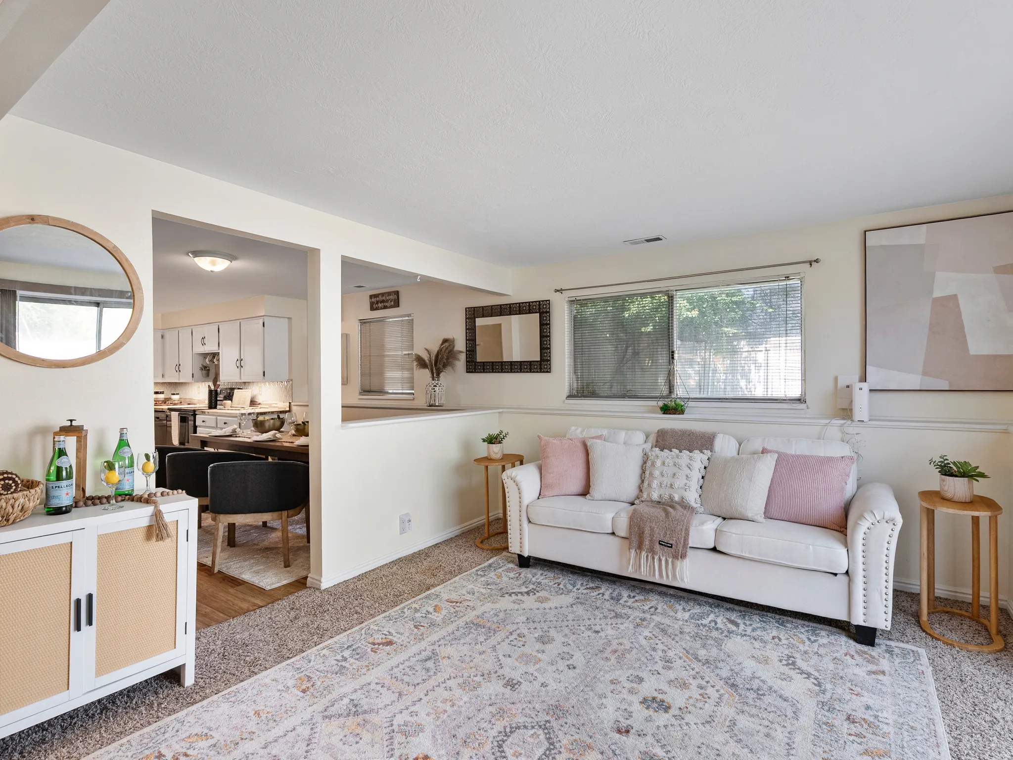 Carpeted living area featuring a large window, a partial wall partition, and an opening to an adjacent room with wood-finish flooring