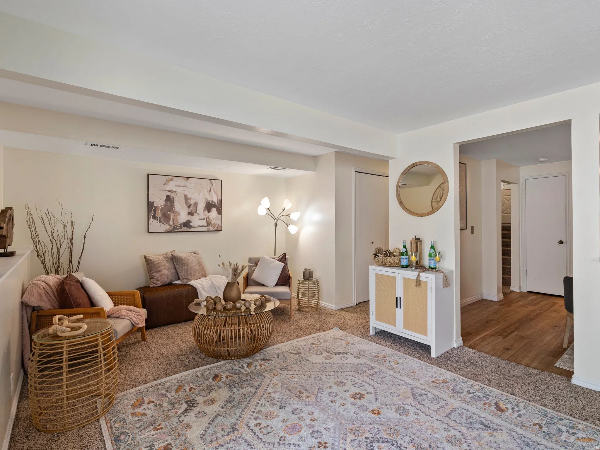 Carpeted living area featuring a neutral color palette, recessed lighting, and an archway leading to wood-finish flooring