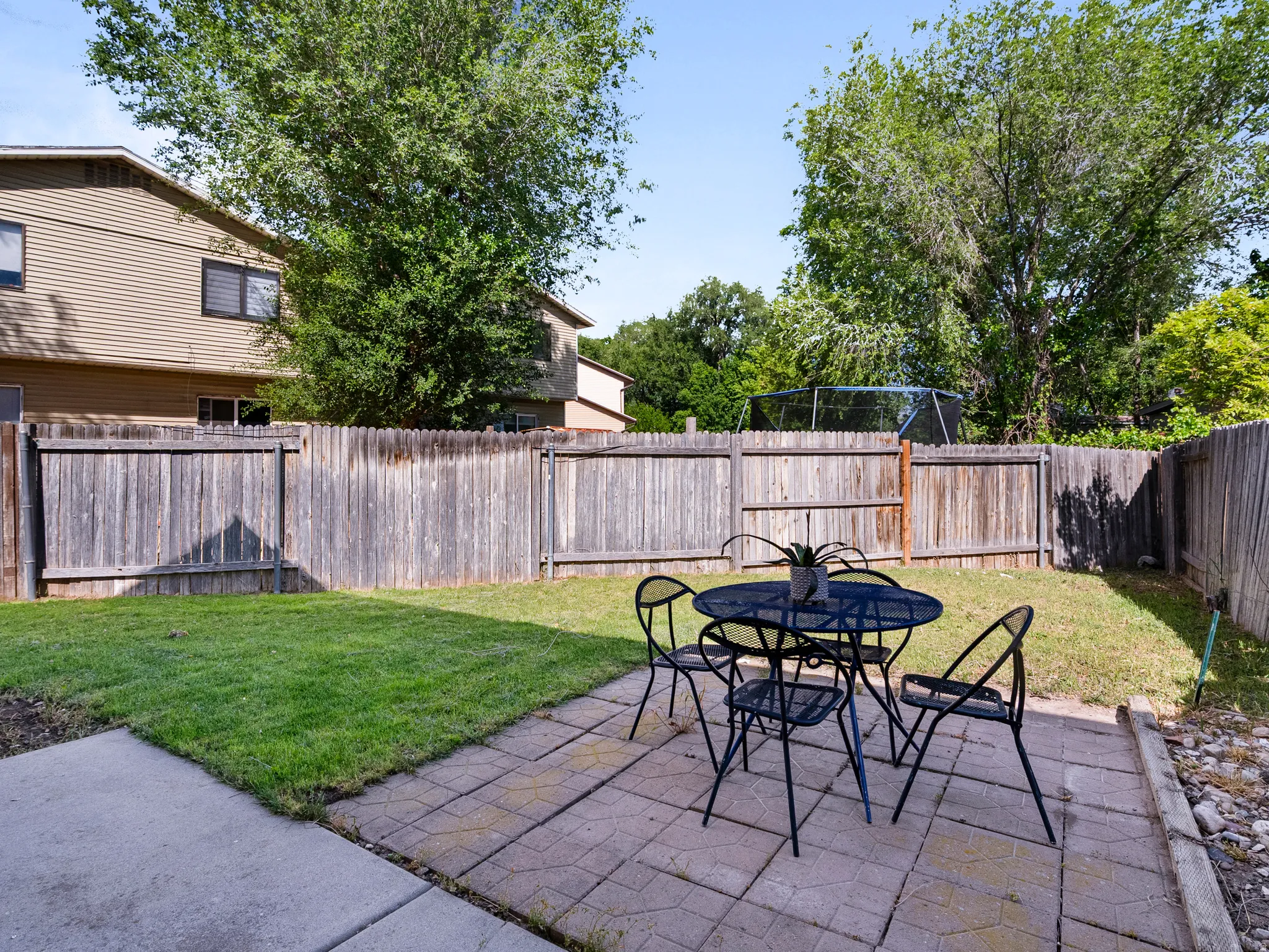 Private backyard featuring a paver patio area, a manicured lawn, and a wood privacy fence