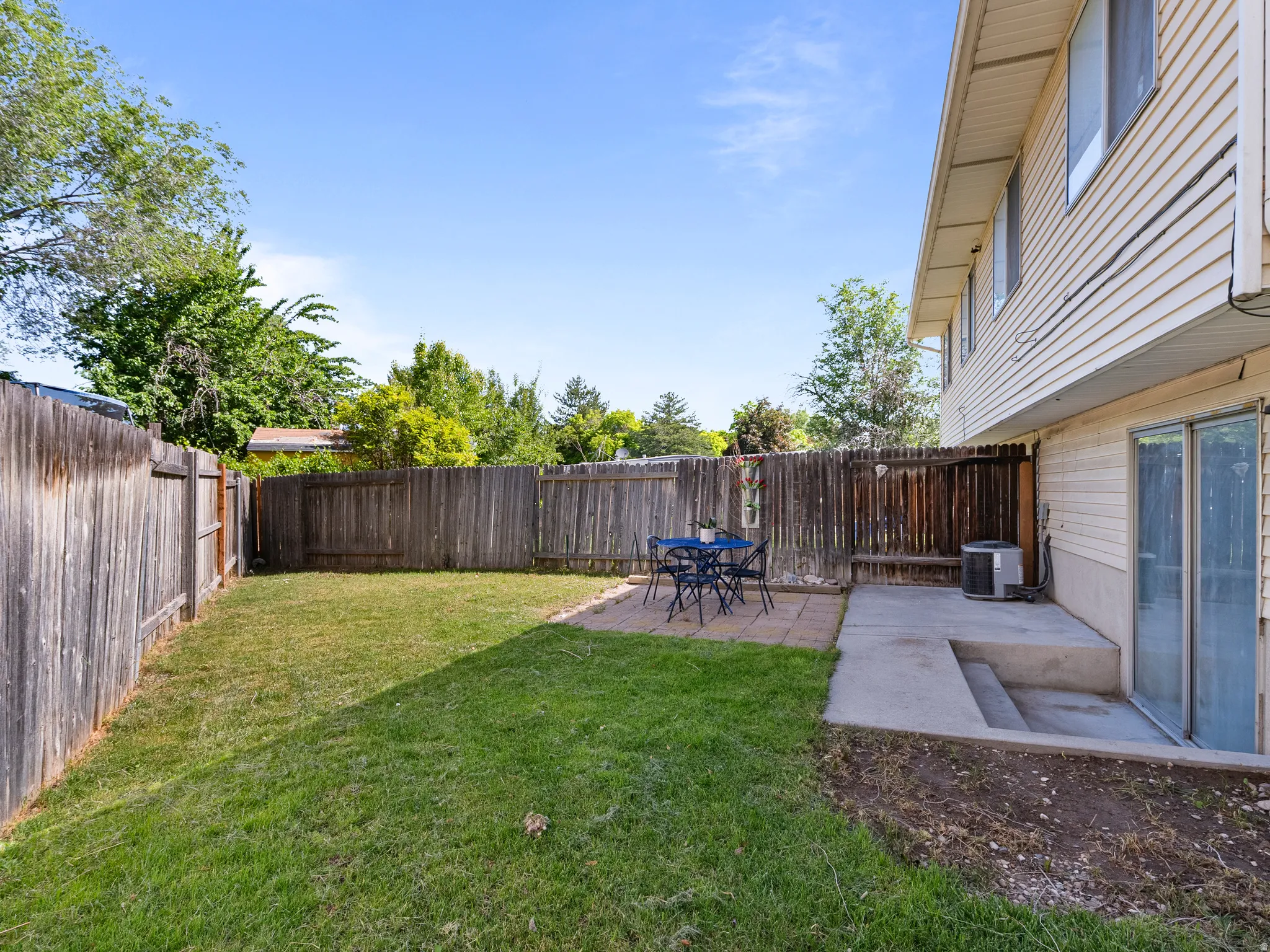 Private backyard featuring a wooden privacy fence, a concrete patio area, and a sliding glass door entry