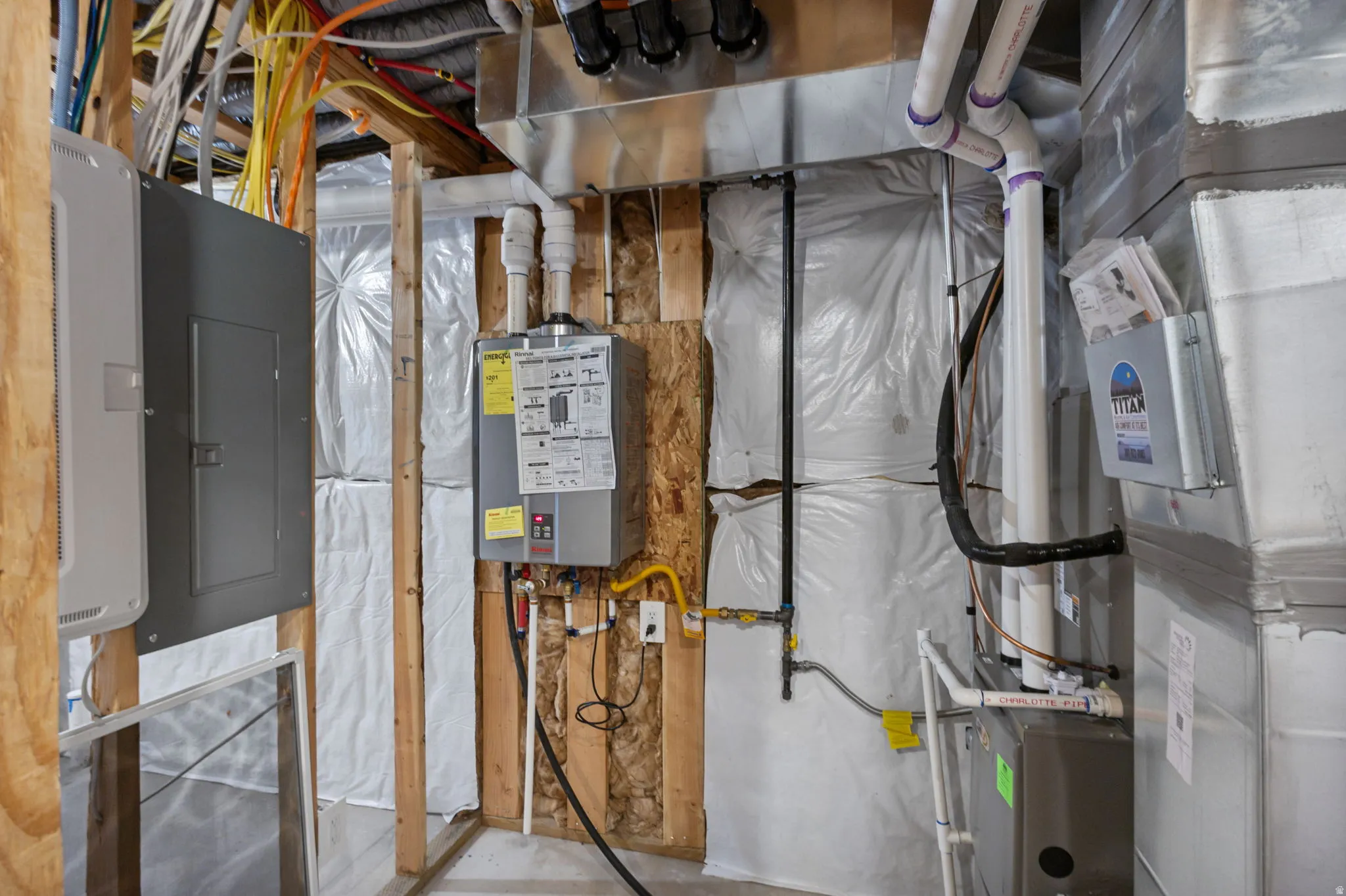 Basement utility area featuring exposed wood framing, multiple electrical panels, and a tankless water heater
