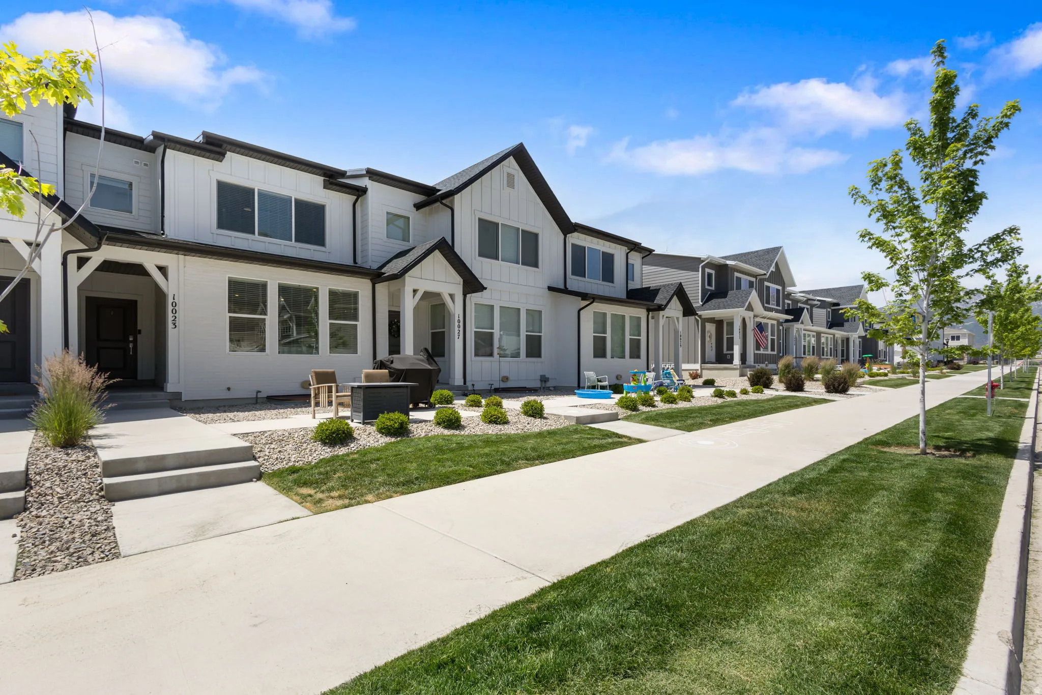 Modern townhome exterior featuring white siding with black trim accents and a covered entryway