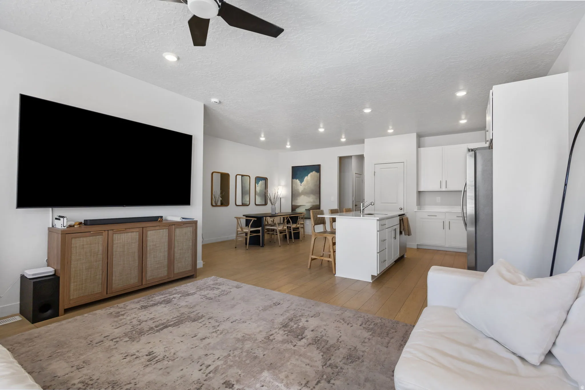 Open-concept living space featuring wood-finish flooring, recessed lighting, and a ceiling fan