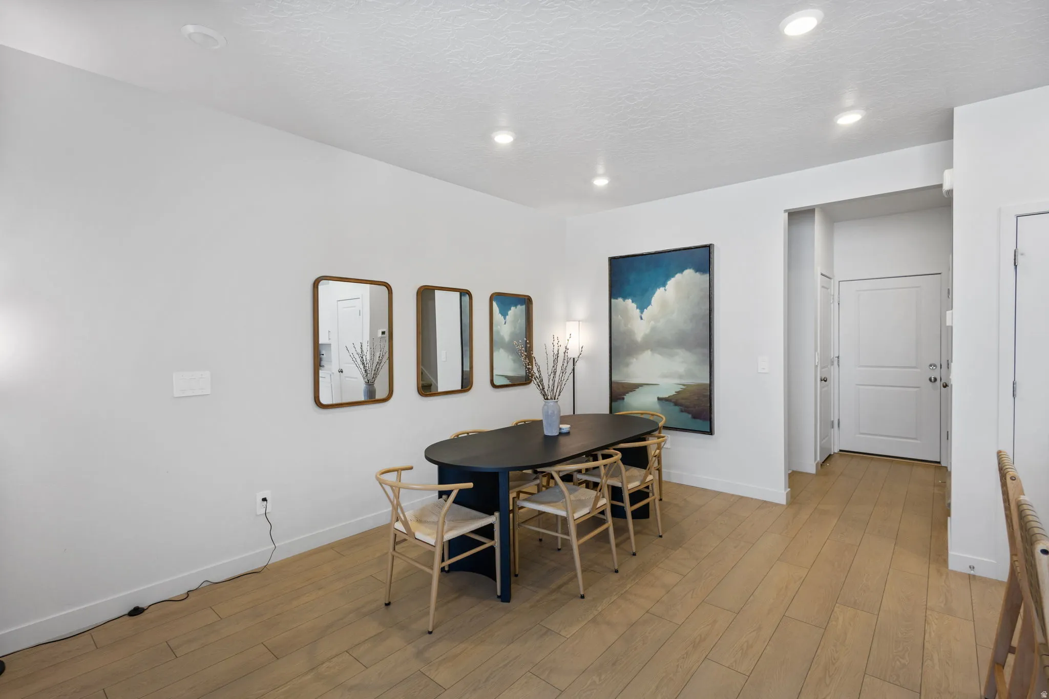 Bright interior space featuring light wood-finish flooring, recessed lighting, and a white paneled door