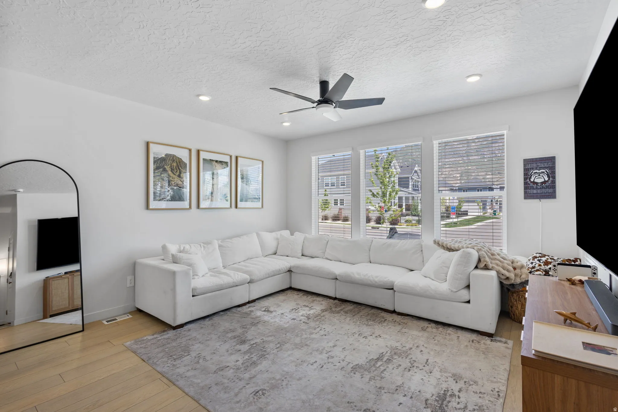 Bright living space featuring light wood-finish flooring, recessed lighting, and a ceiling fan
