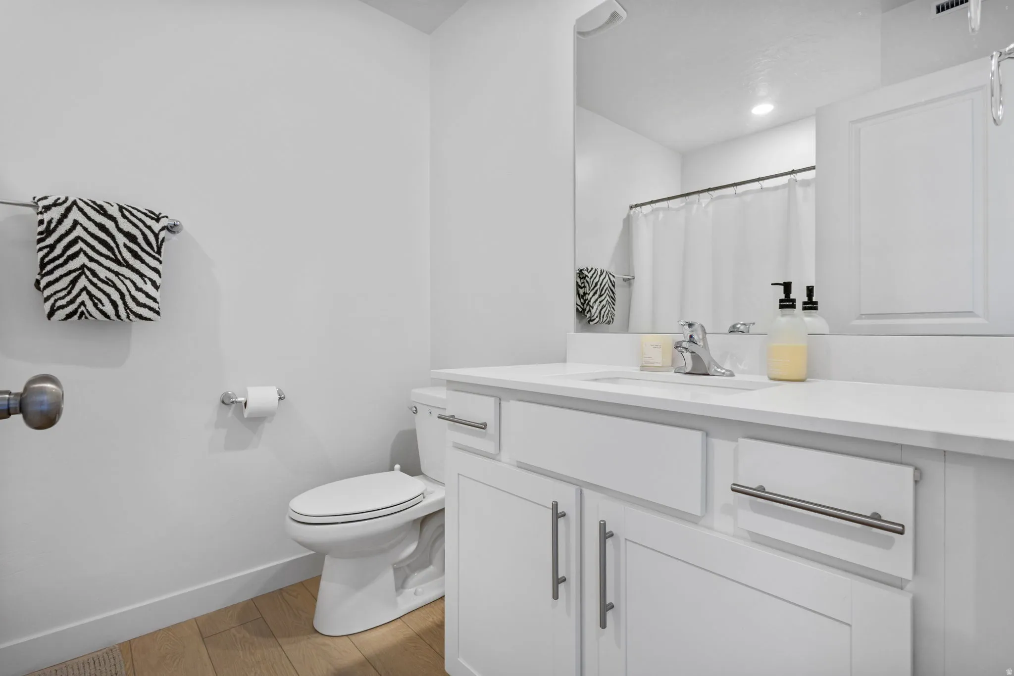White vanity with a single sink, chrome faucet, and integrated countertop
