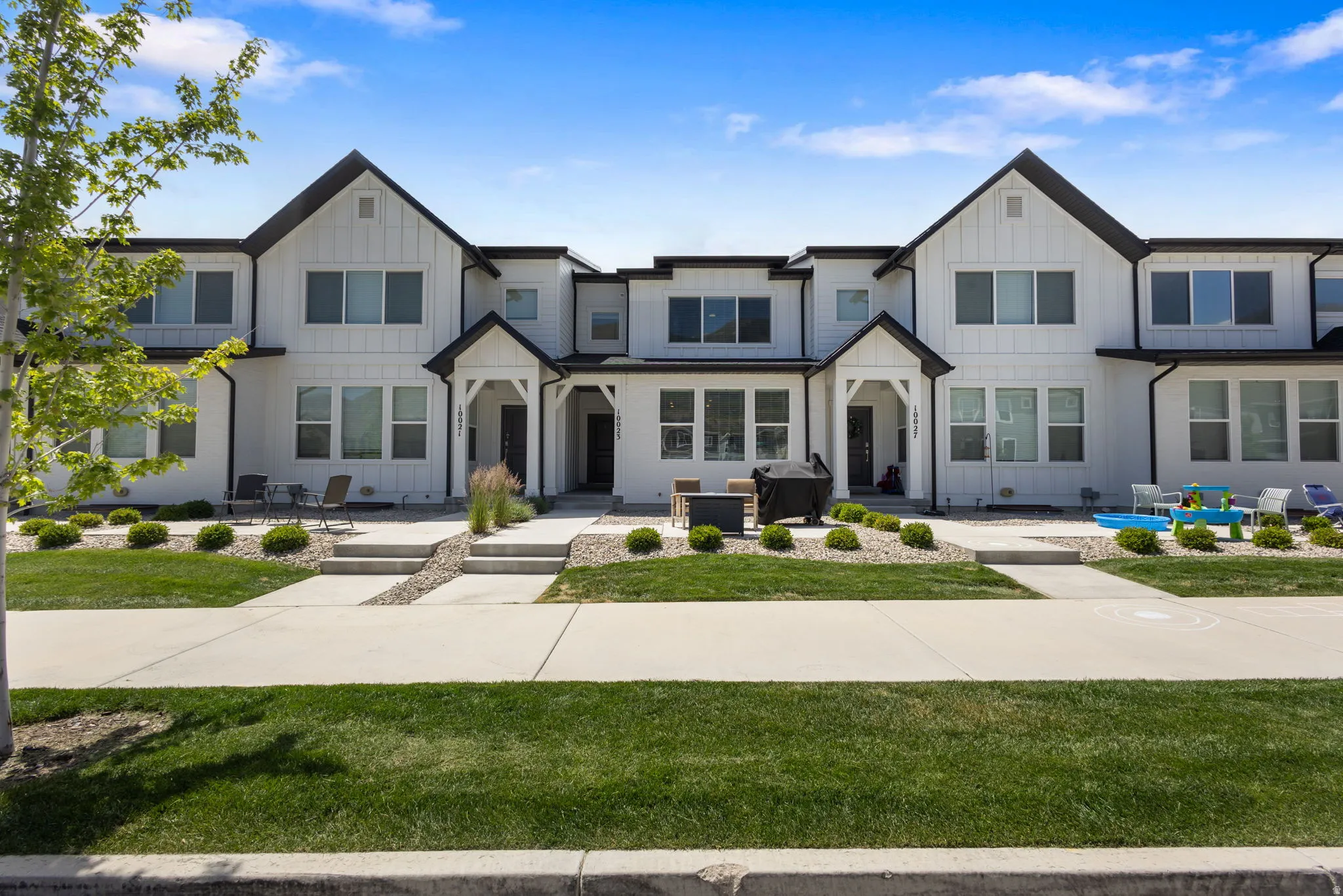 Modern townhome exterior featuring vertical white siding, contrasting black trim, multiple windows, and a covered entryway