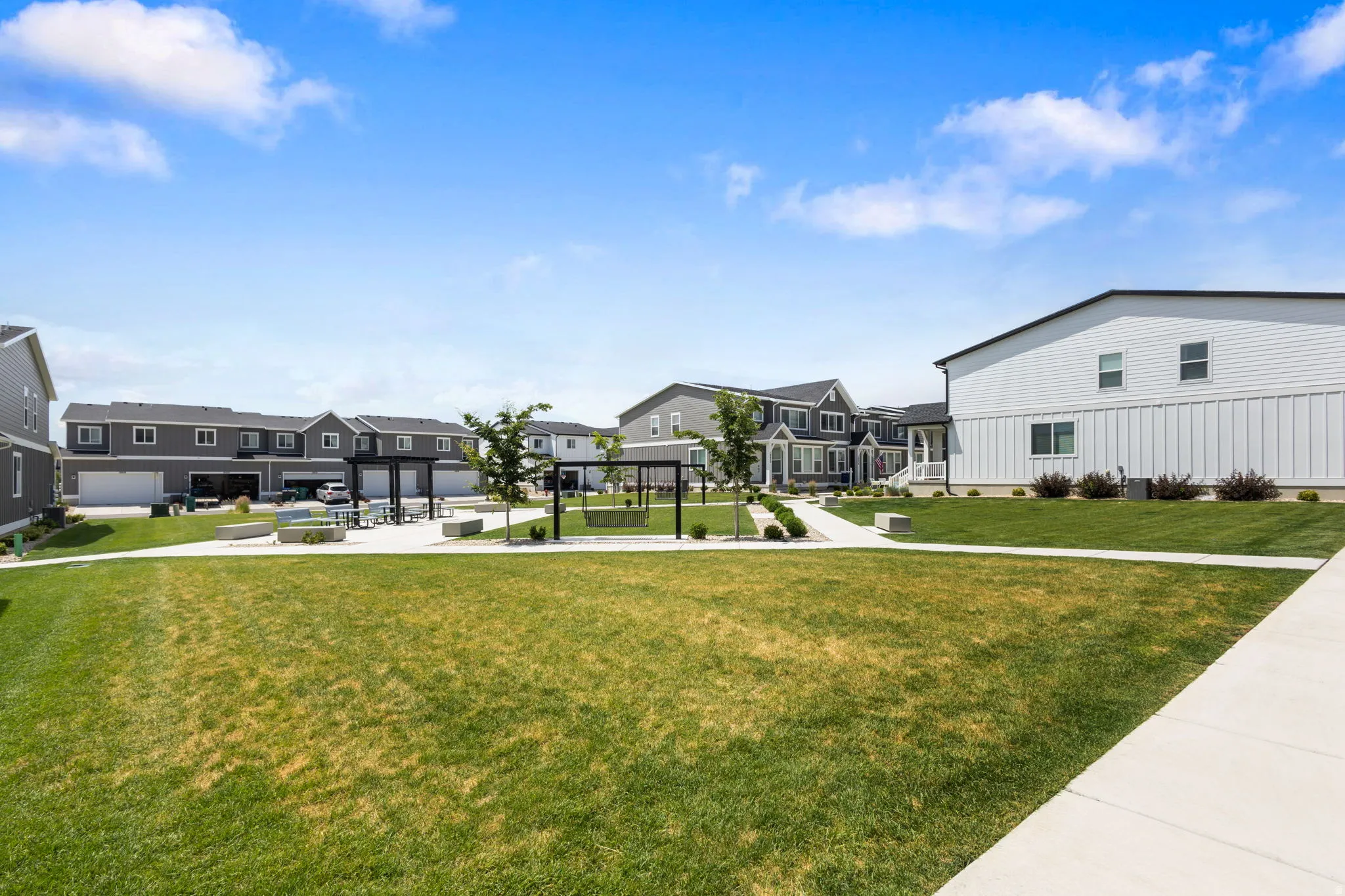 Expansive green space featuring a concrete pathway, a structured pergola, and low-lying shrubs