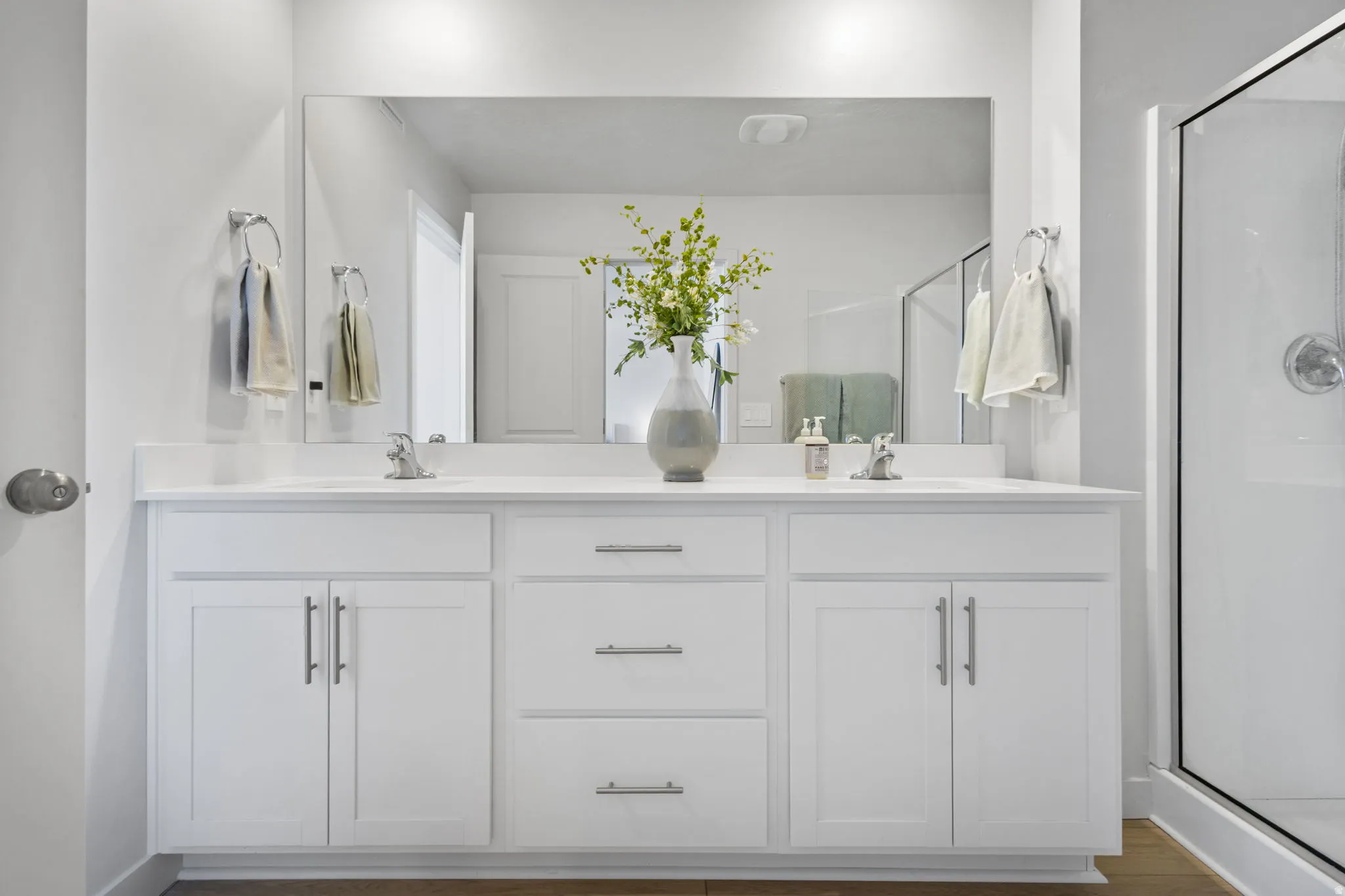 Double vanity with white cabinetry, brushed nickel hardware, and a large mirror