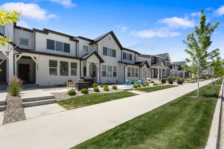 Modern townhome exterior featuring white siding with black trim accents and a covered entryway