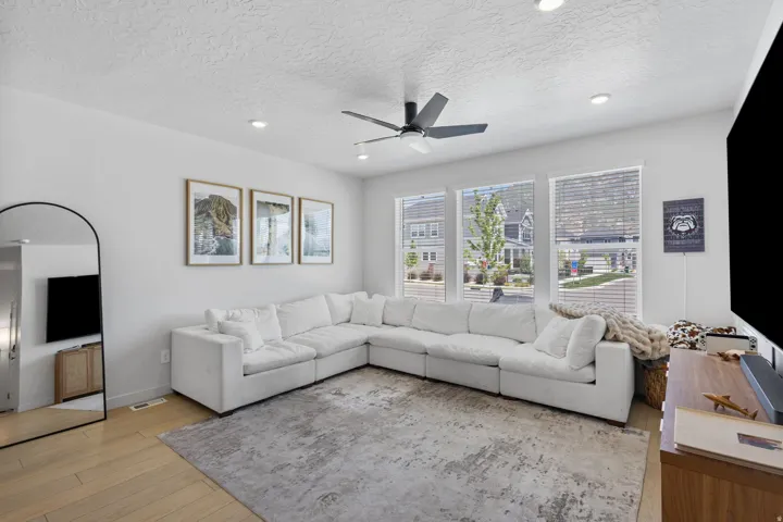 Bright living space featuring light wood-finish flooring, recessed lighting, and a ceiling fan