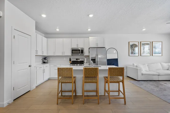 Modern kitchen featuring white cabinetry, stainless steel appliances, a center island with bar seating, recessed lighting, and wood-finish flooring