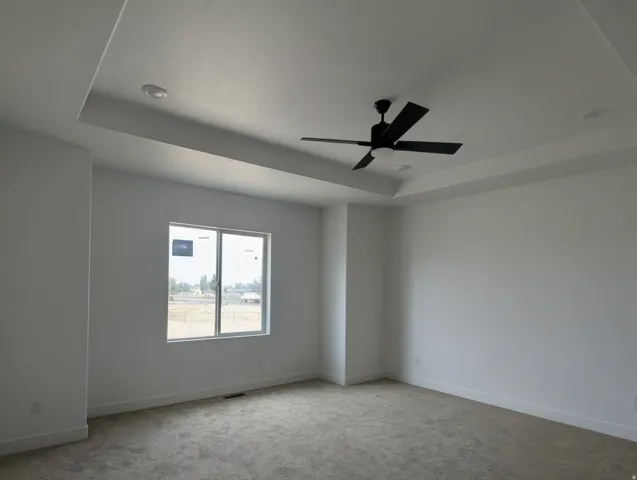 Spacious room featuring a tray ceiling, recessed lighting, and a modern ceiling fan