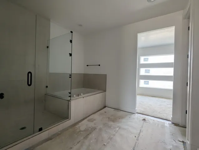 Spacious bathroom featuring a glass-enclosed shower with black fixtures and a built-in tub