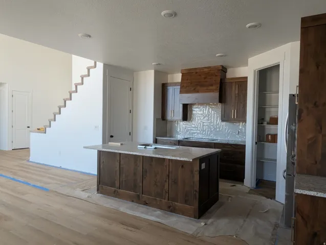 Kitchen featuring a center island with a light-toned countertop, wood-finish cabinetry, and a custom wood-finish range hood