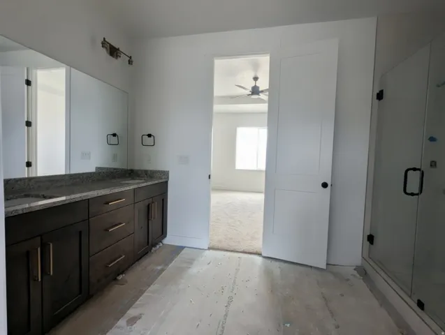 Double vanity with dark wood cabinetry and stone countertops