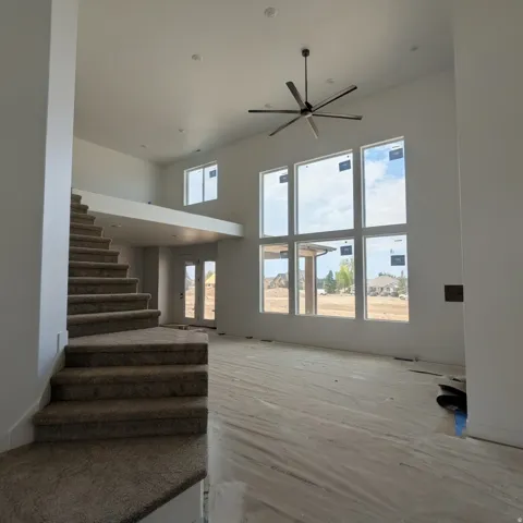 Two-story living area featuring a vaulted ceiling and a large ceiling fan