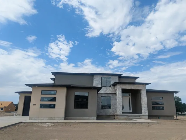 Modern architectural exterior with a tiered roofline, featuring a combination of smooth stucco and stone veneer finishes