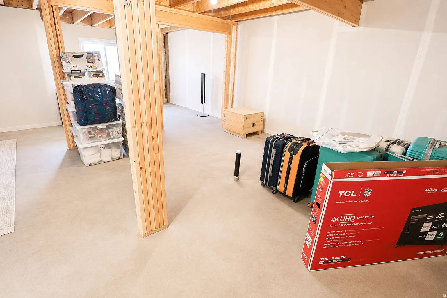 Unfinished interior space featuring exposed wooden structural beams, drywall, and concrete flooring