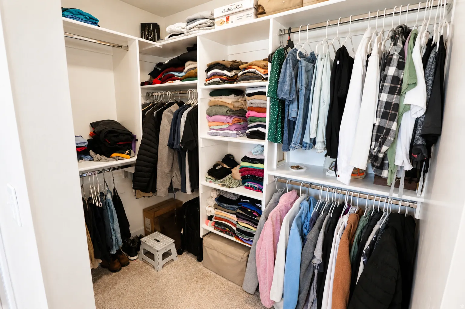 Walk-in closet featuring built-in shelving, multiple hanging rods, and neutral-toned carpeting