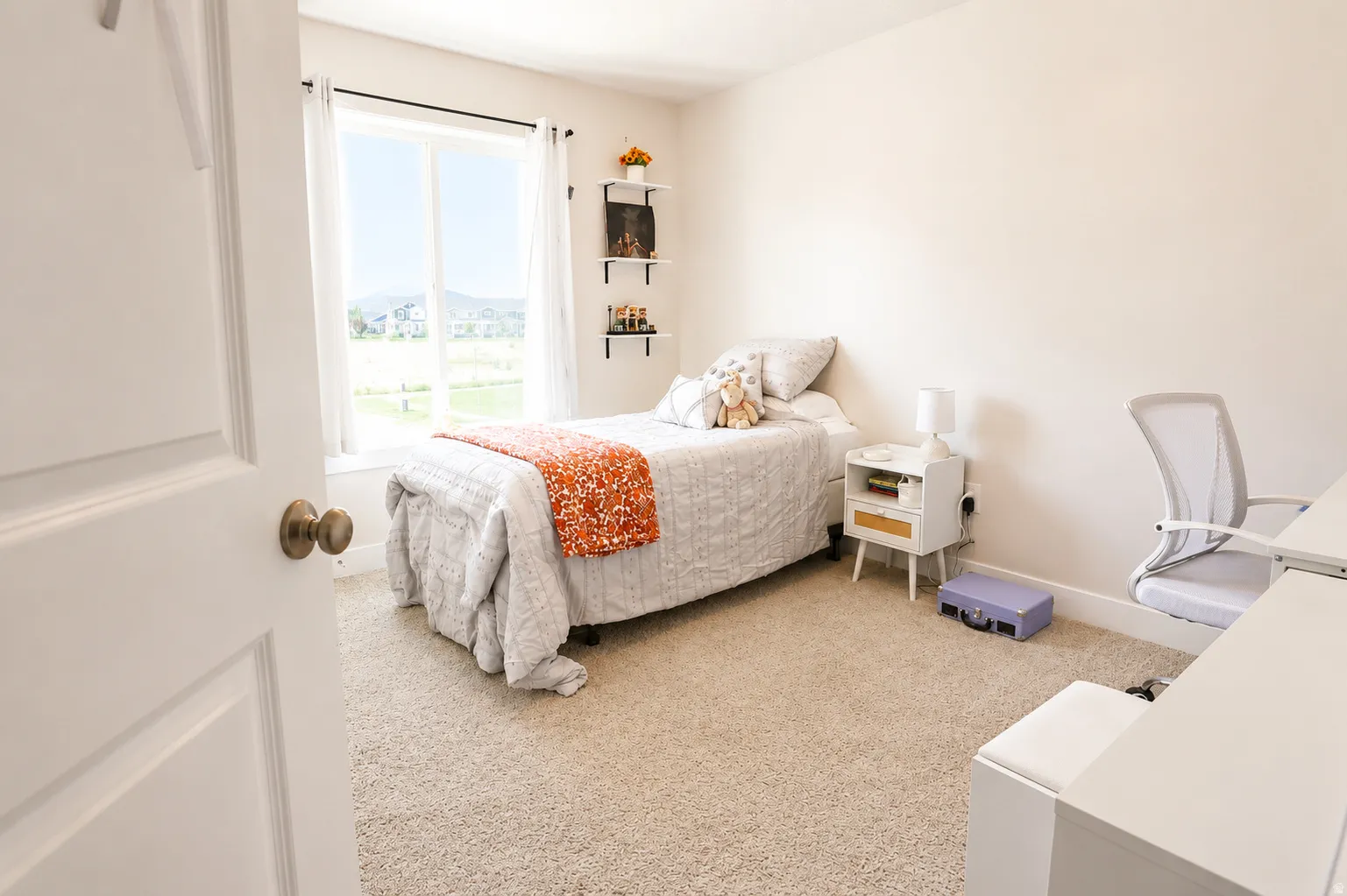 Light-filled interior space featuring a large window, neutral wall paint, and soft carpet flooring
