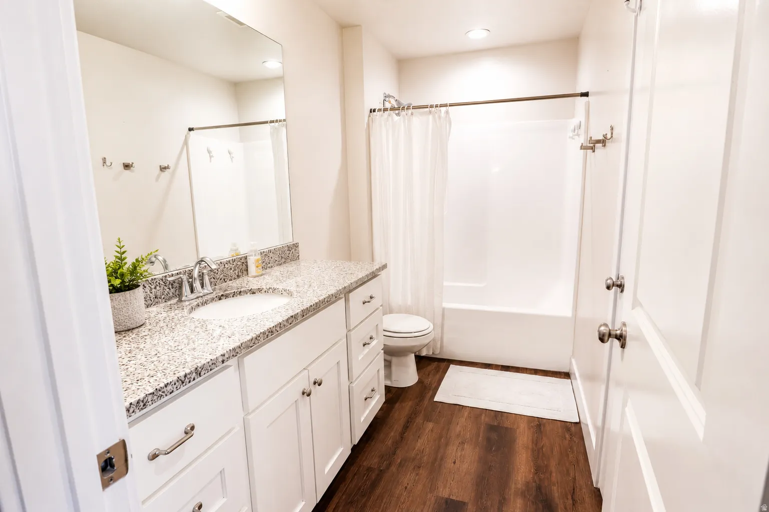 Bathroom featuring a white vanity with granite-finish countertop, under-mount sink, and brushed nickel faucet