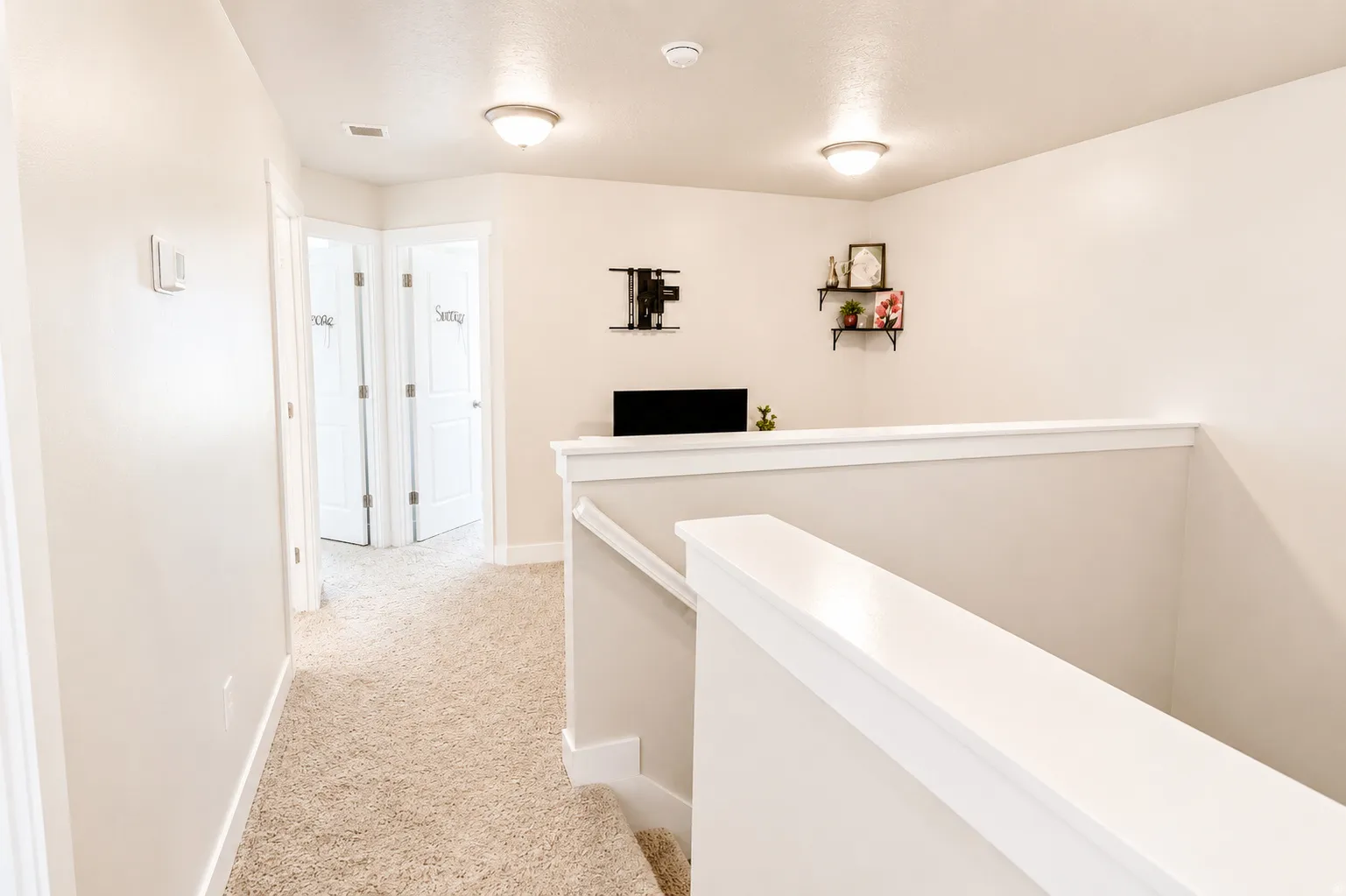 Upper-level hallway featuring neutral-toned carpet, light-colored walls, white trim, and flush-mount lighting fixtures