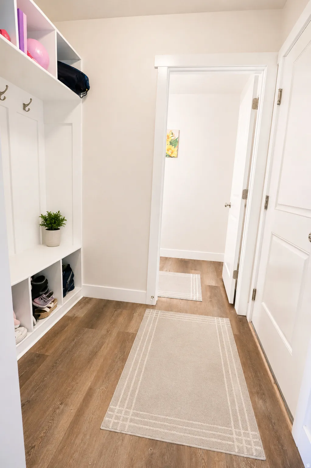Entryway featuring built-in white cabinetry with open shelving and coat hooks