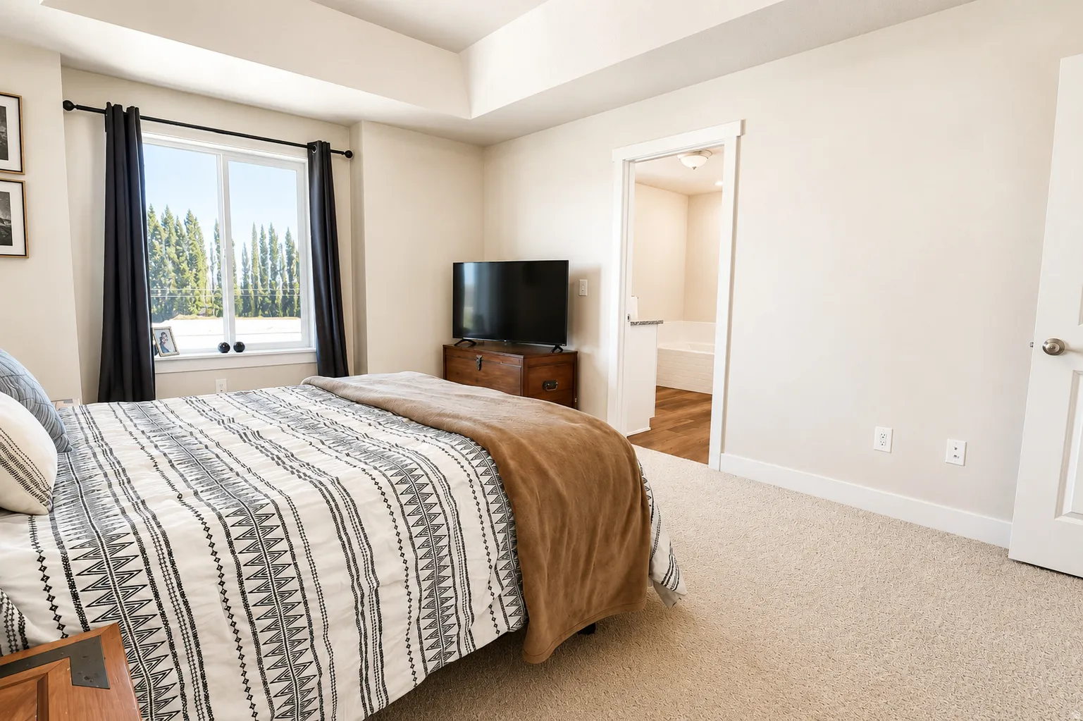 Bedroom featuring neutral carpeting, a large window, and a tray ceiling
