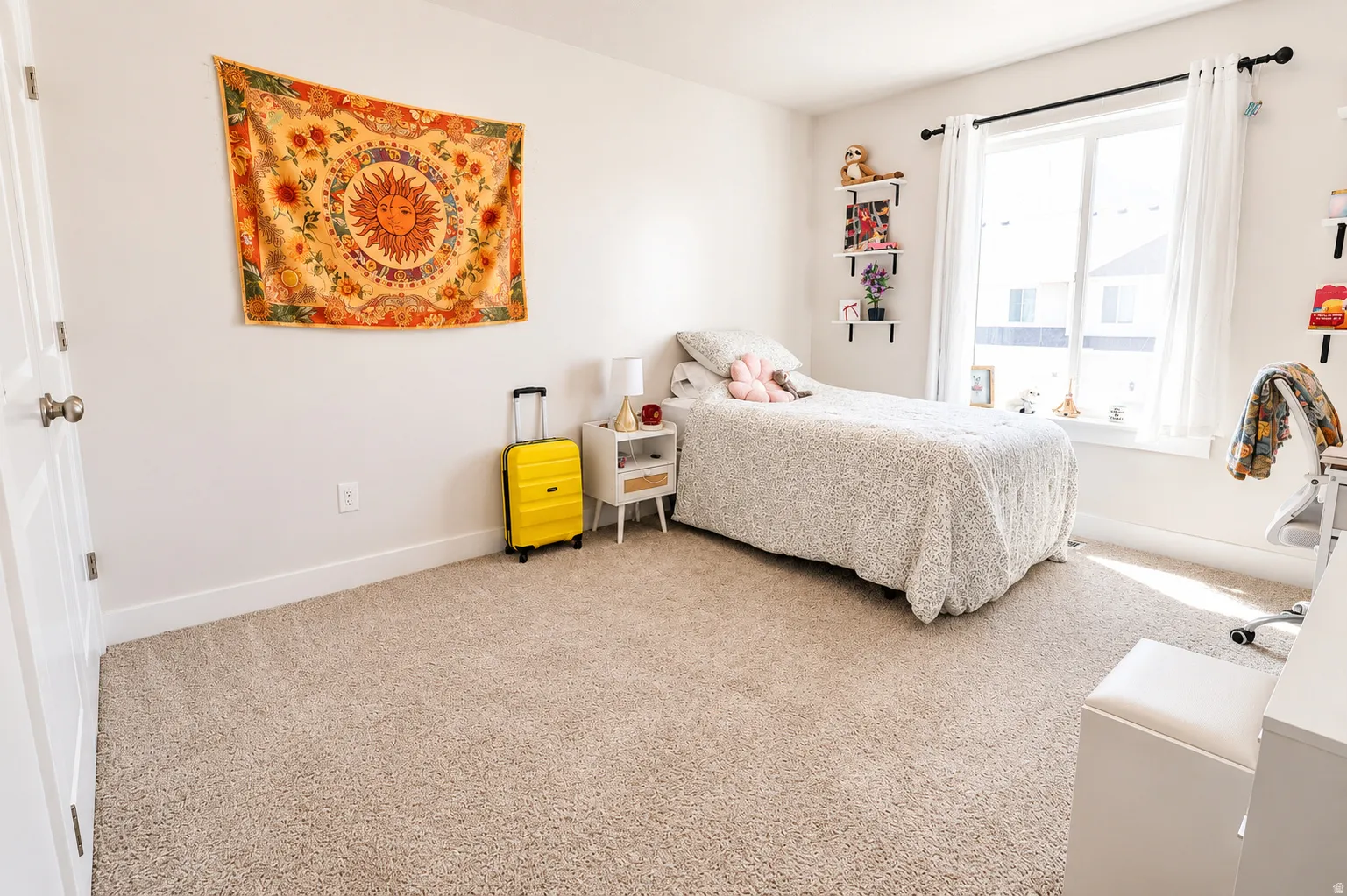Carpeted room featuring a large window with white blinds, white trim, and a white interior door