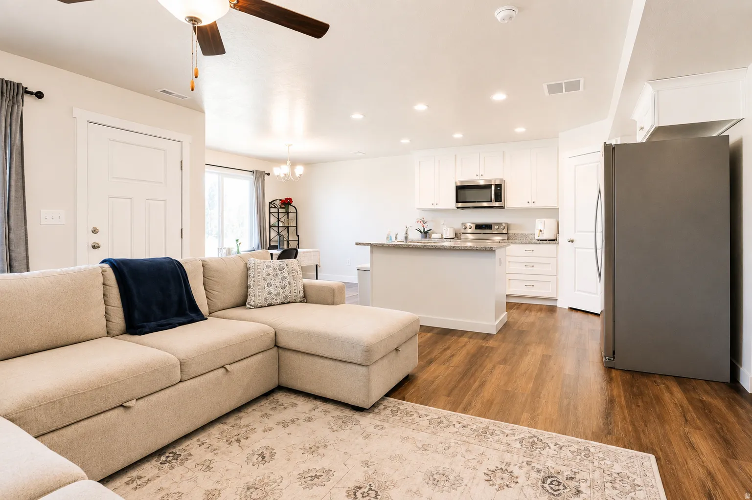 Open-concept living space featuring wood-finish flooring, recessed lighting, and a ceiling fan