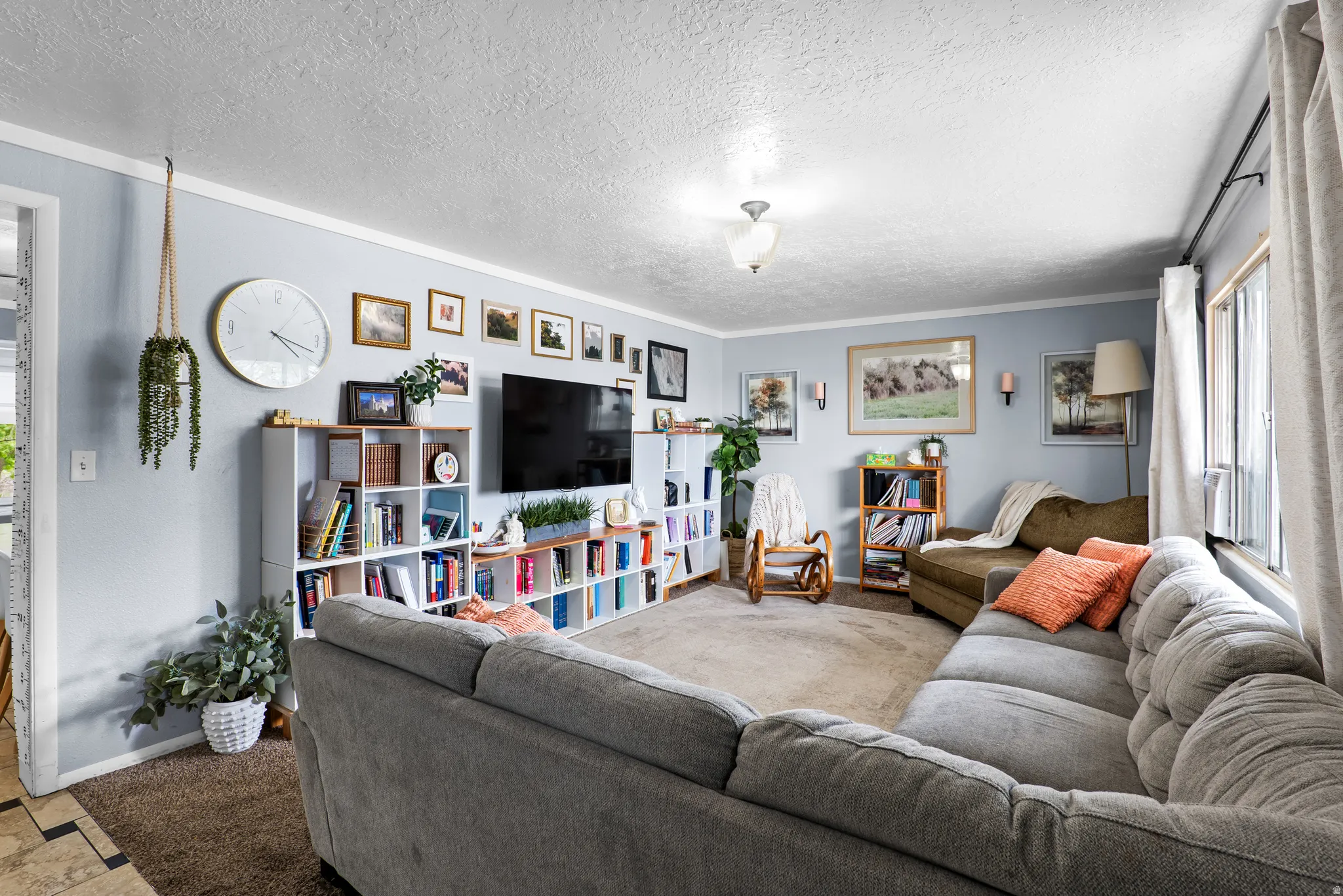 Spacious living area featuring light blue walls, white crown molding, and a textured ceiling
