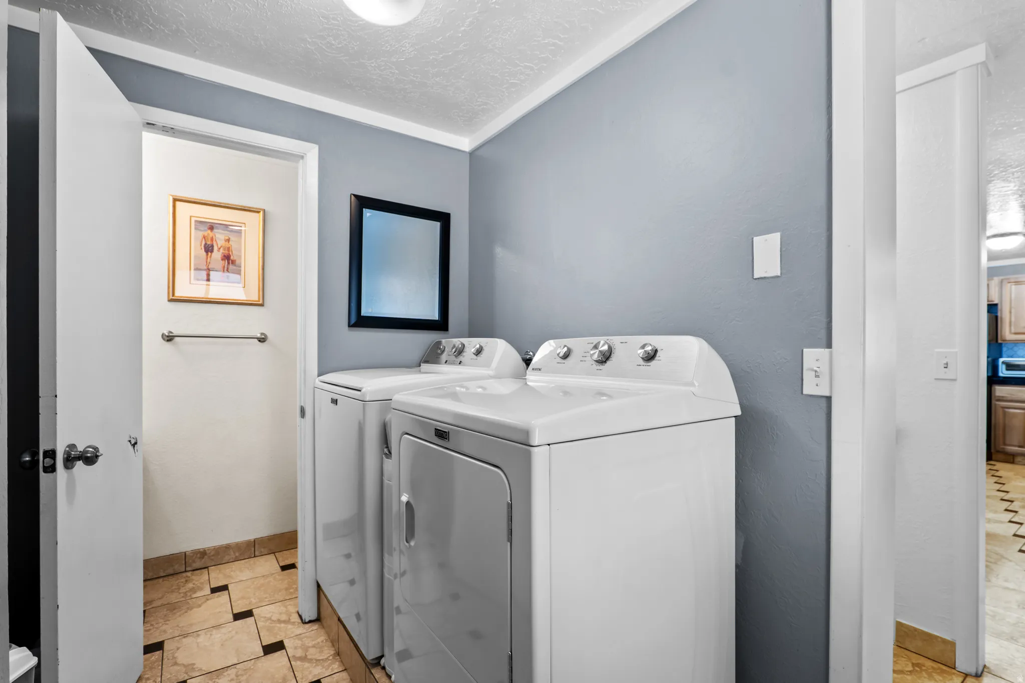 Laundry area featuring a side-by-side washer and dryer, tile flooring, and light blue wall paint