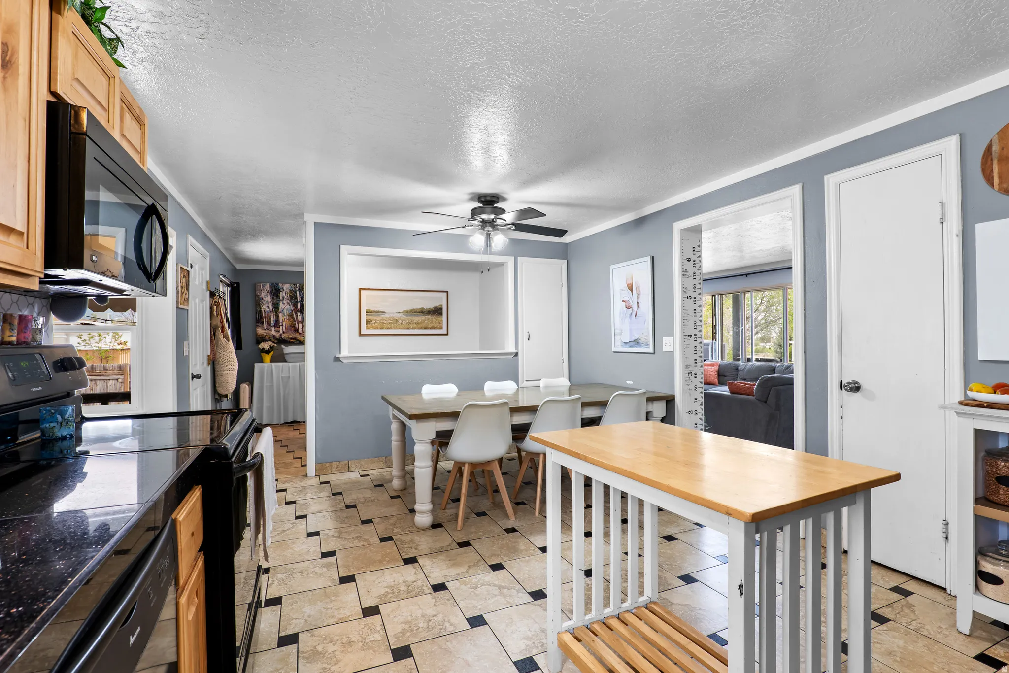 Kitchen featuring wood cabinetry, black appliances, dark speckled countertops, and a tiled floor with a checkered pattern