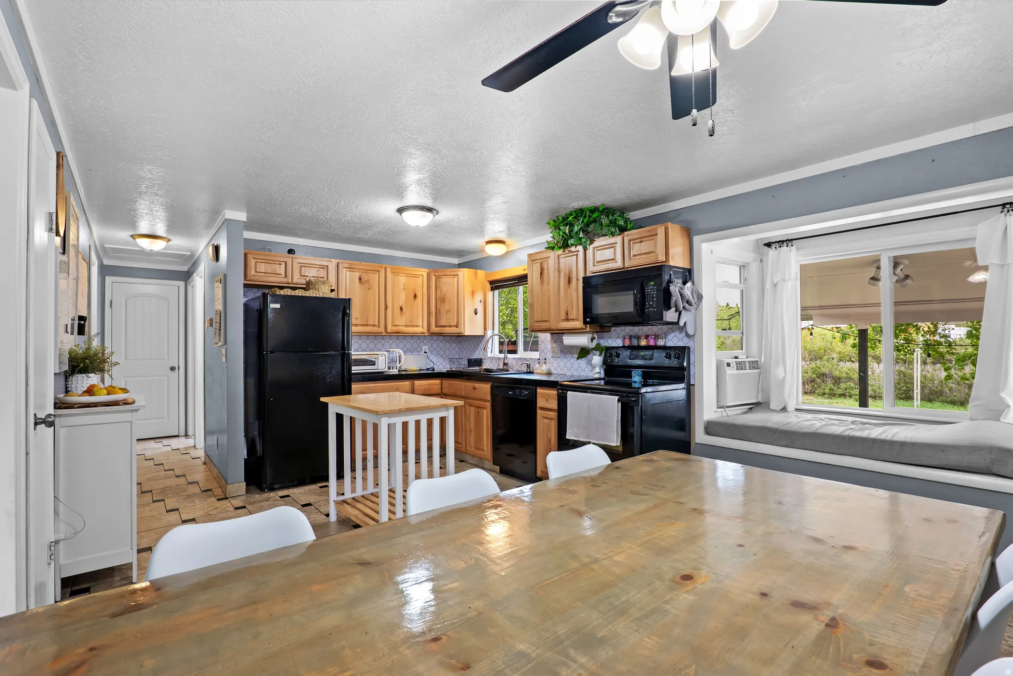 Kitchen area featuring wood cabinetry, black appliances, a tiled backsplash, and recessed lighting