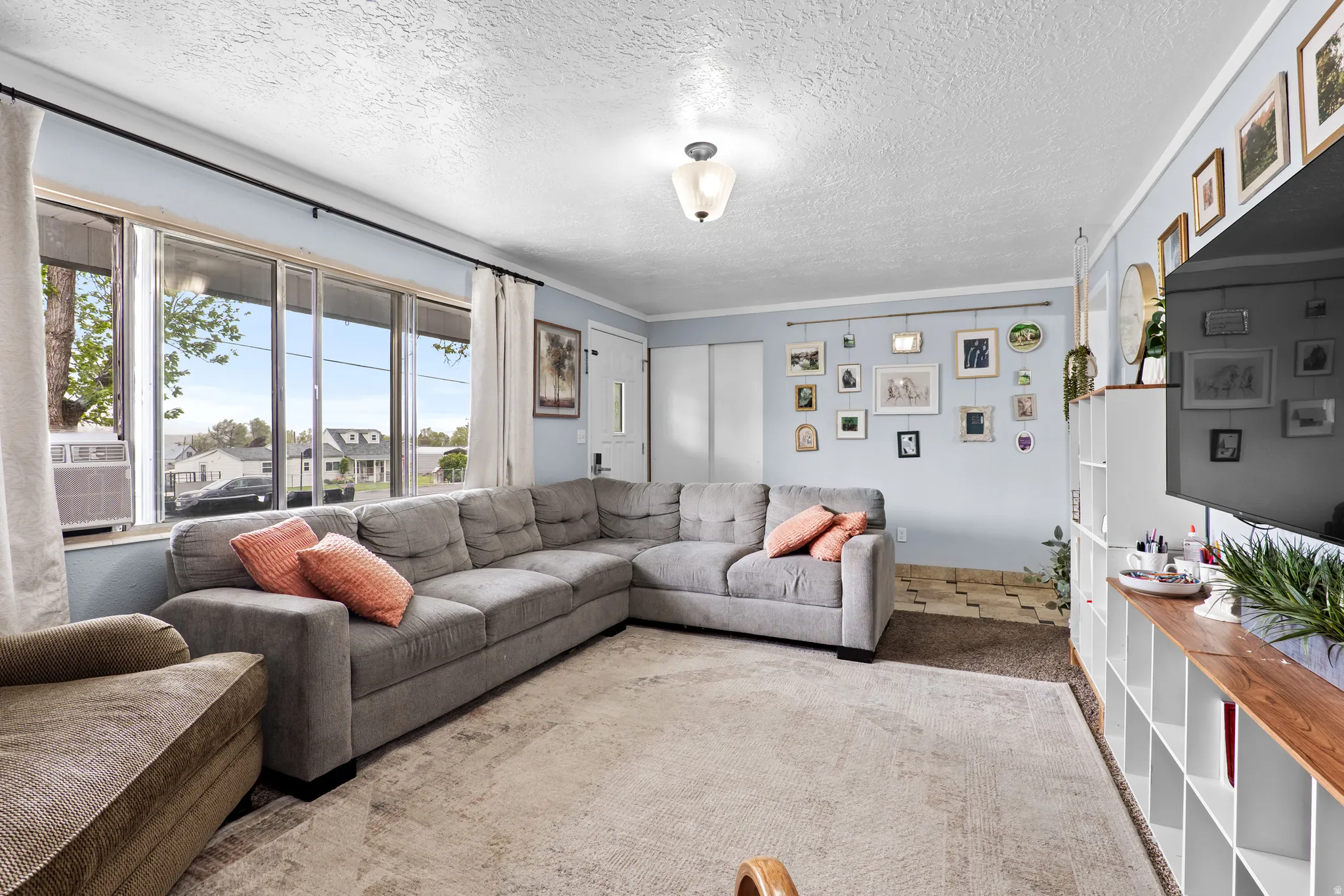 Living room featuring large picture windows, light blue wall paint, and overhead ceiling lighting