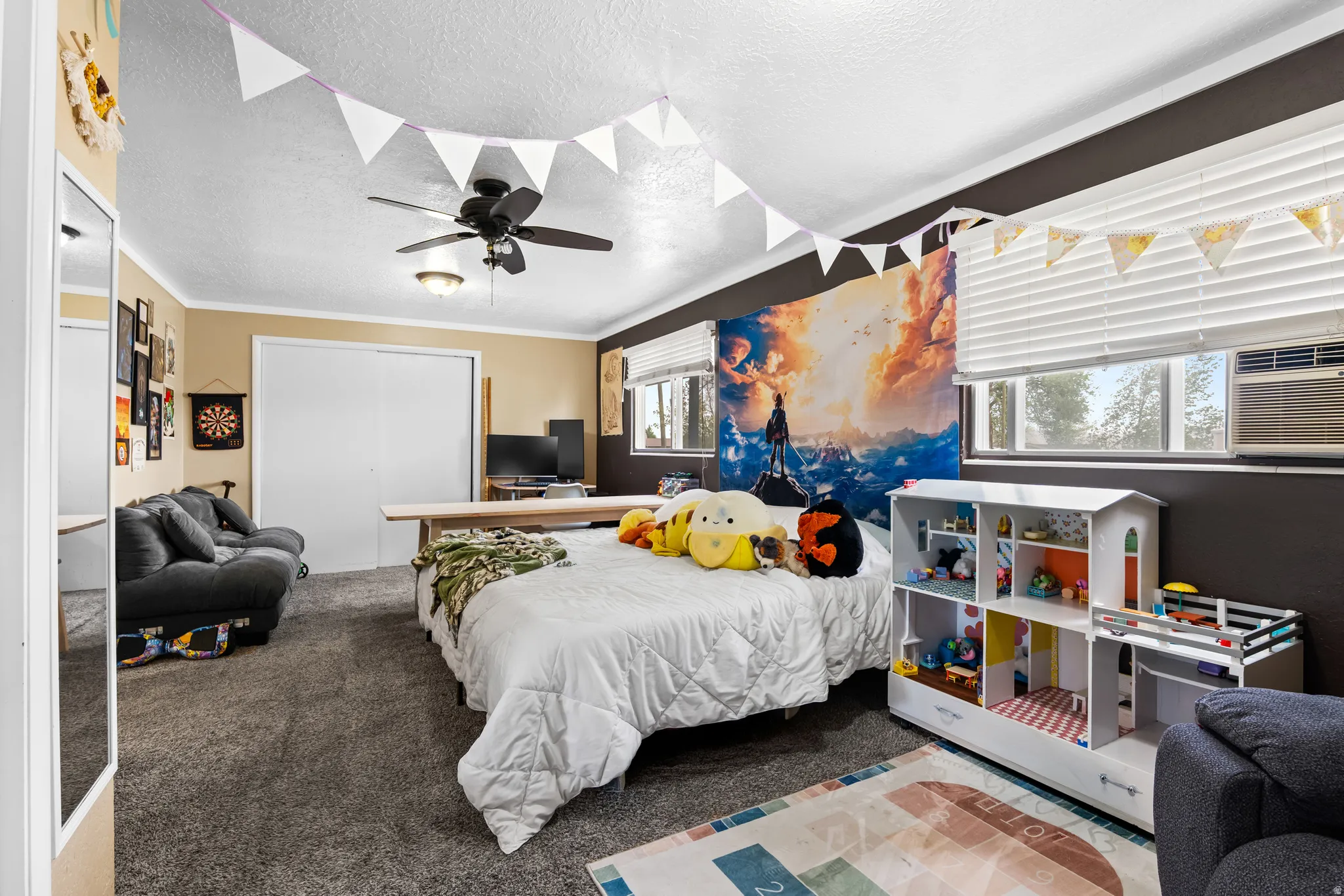 Carpeted room featuring a ceiling fan, dual windows with blinds, a wall-mounted air conditioning unit, and a built-in closet with sliding doors
